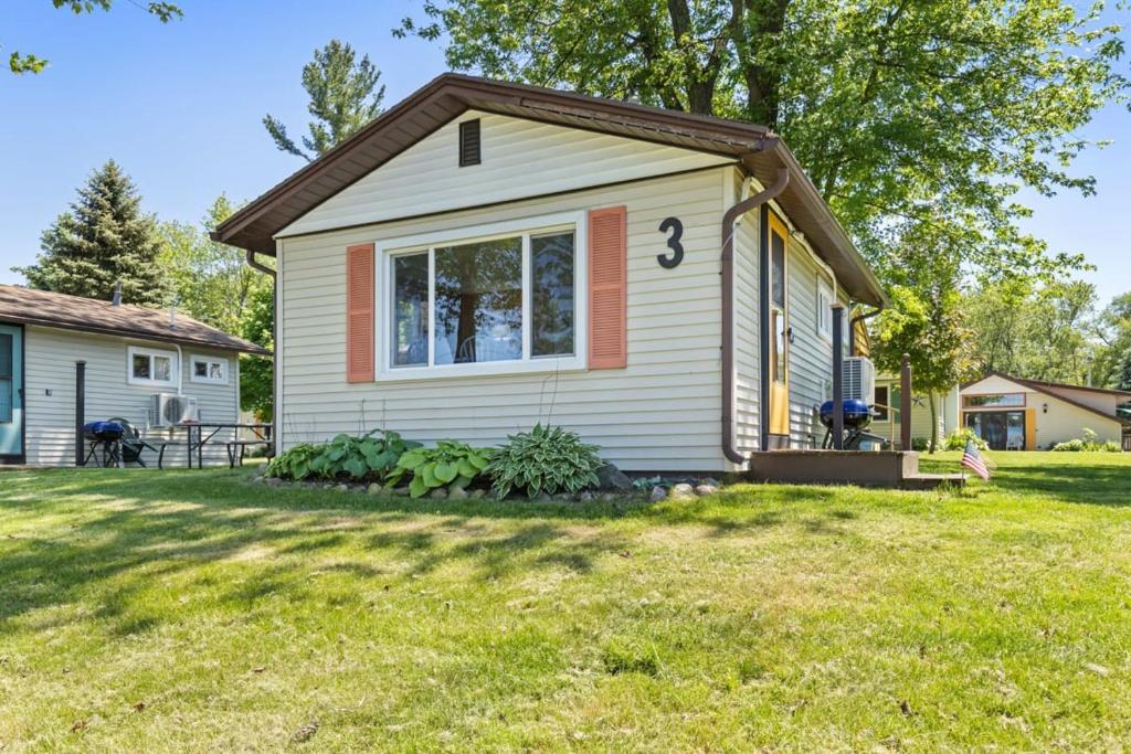 a small house in a yard with a green lawn at Cottage on Chippewa lake with kayaks in Chippewa Lake