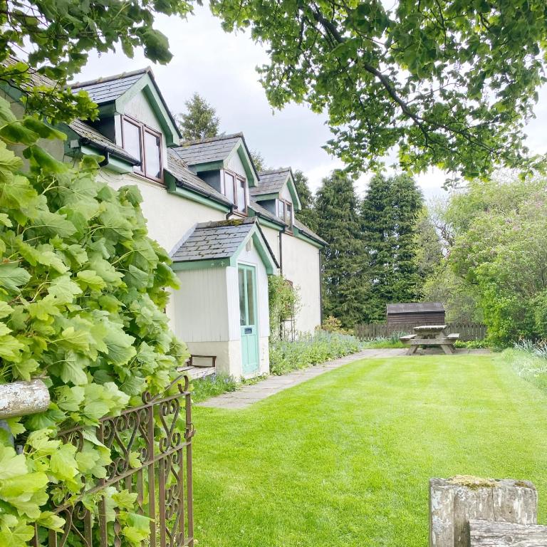 a house with a garden and a bench in the yard at Llynhillyn Cottage in Presteigne