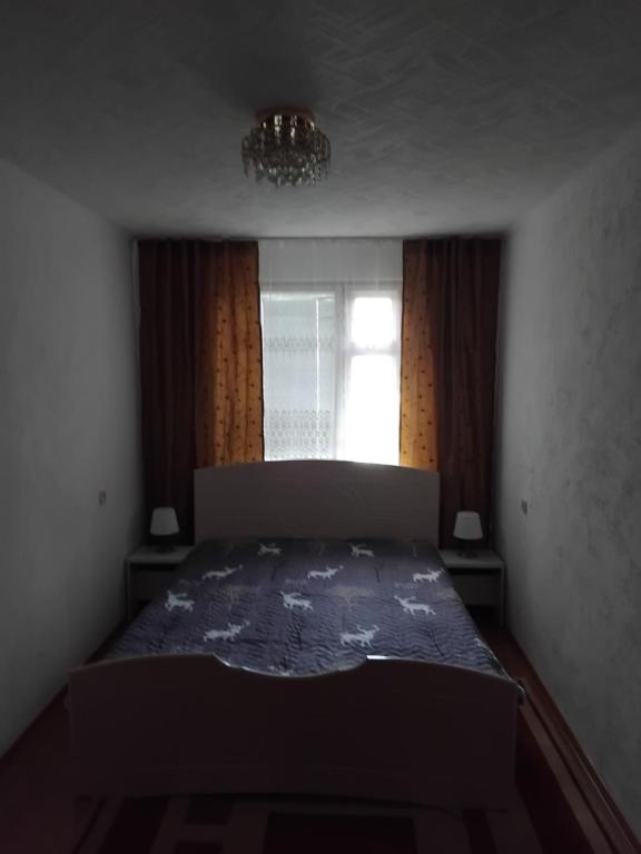a bedroom with a bed and a window at Двухкомнатная квартира in Uralsk