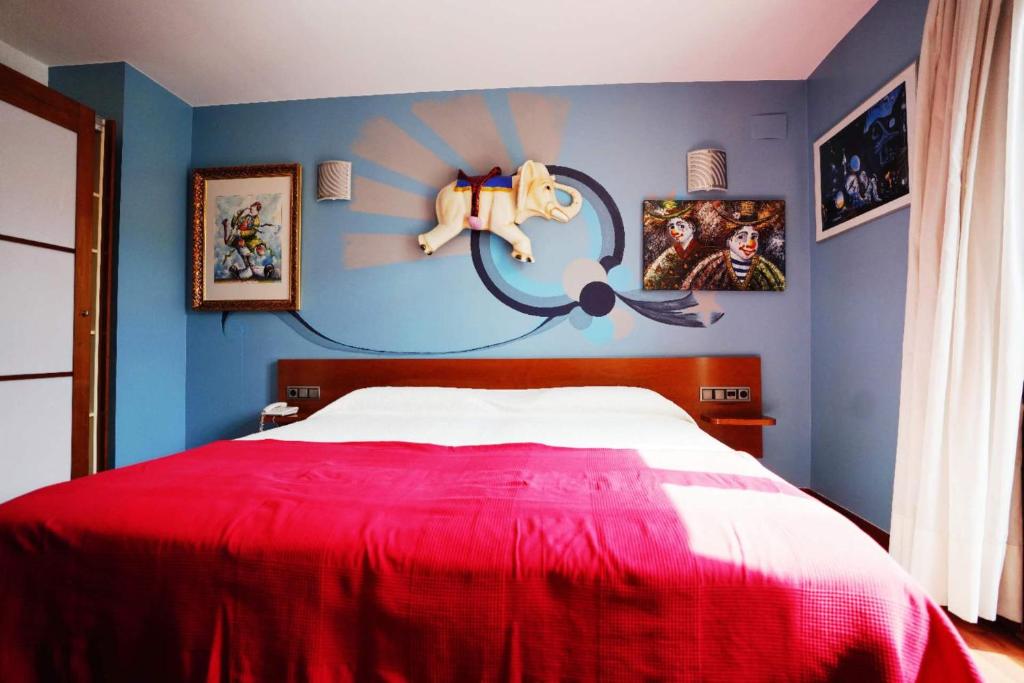 1 dormitorio con cama roja y pared azul en Hotel Plaza Inn, en Figueres