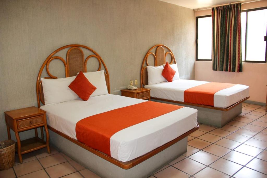 a hotel room with two beds and two windows at Hotel Huautla de Oaxaca in Oaxaca City