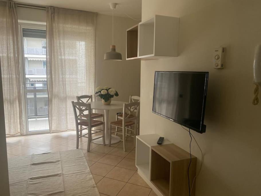 Una sala de estar con un televisor y una mesa con sillas. en Accogliente Appartamento - Milan, en Milán