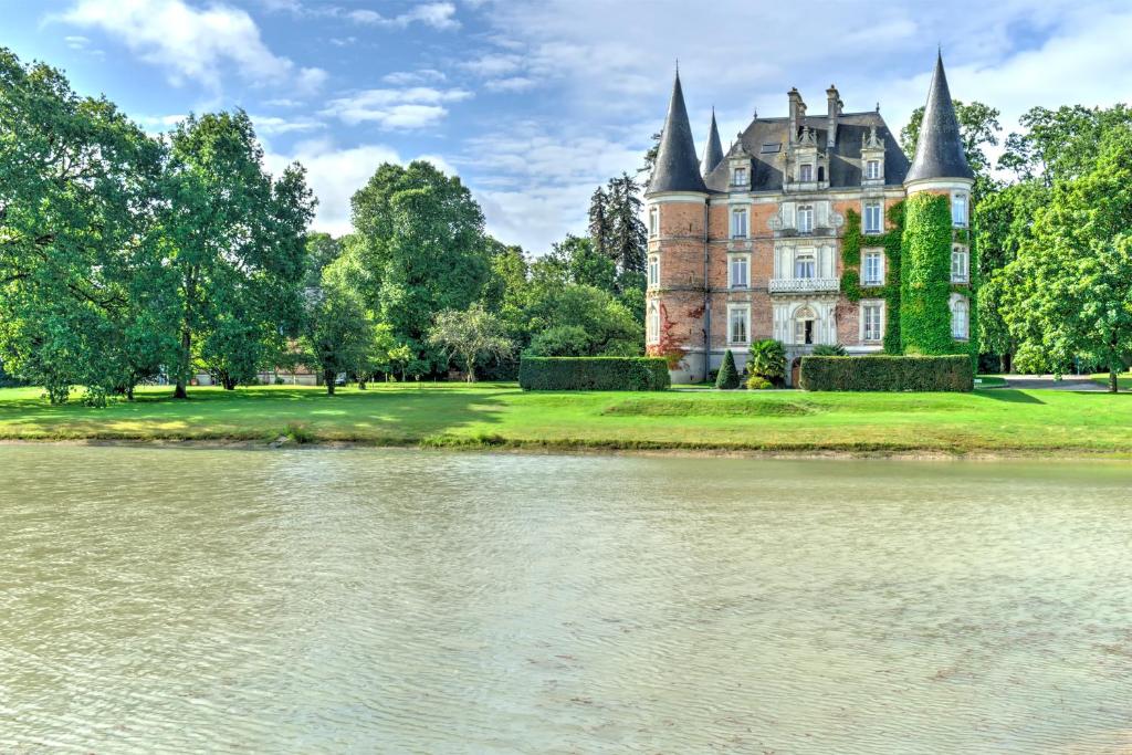 a castle with a lake in front of it at Château D'Apigné Rennes in Le Rheu