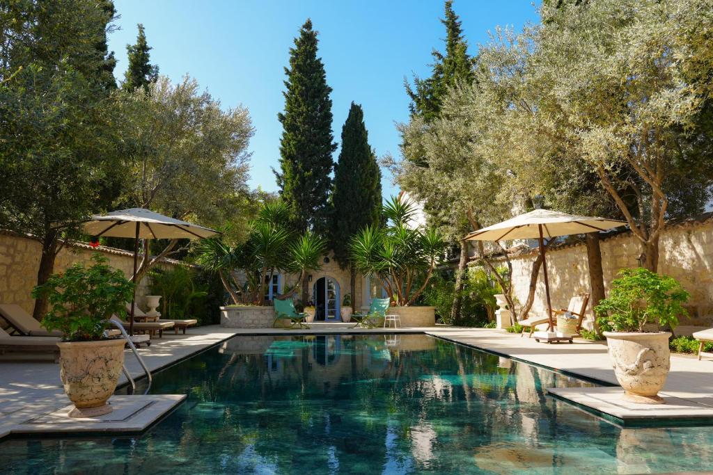 a swimming pool with two umbrellas and trees at Alaçatı Taş Otel in Alacati