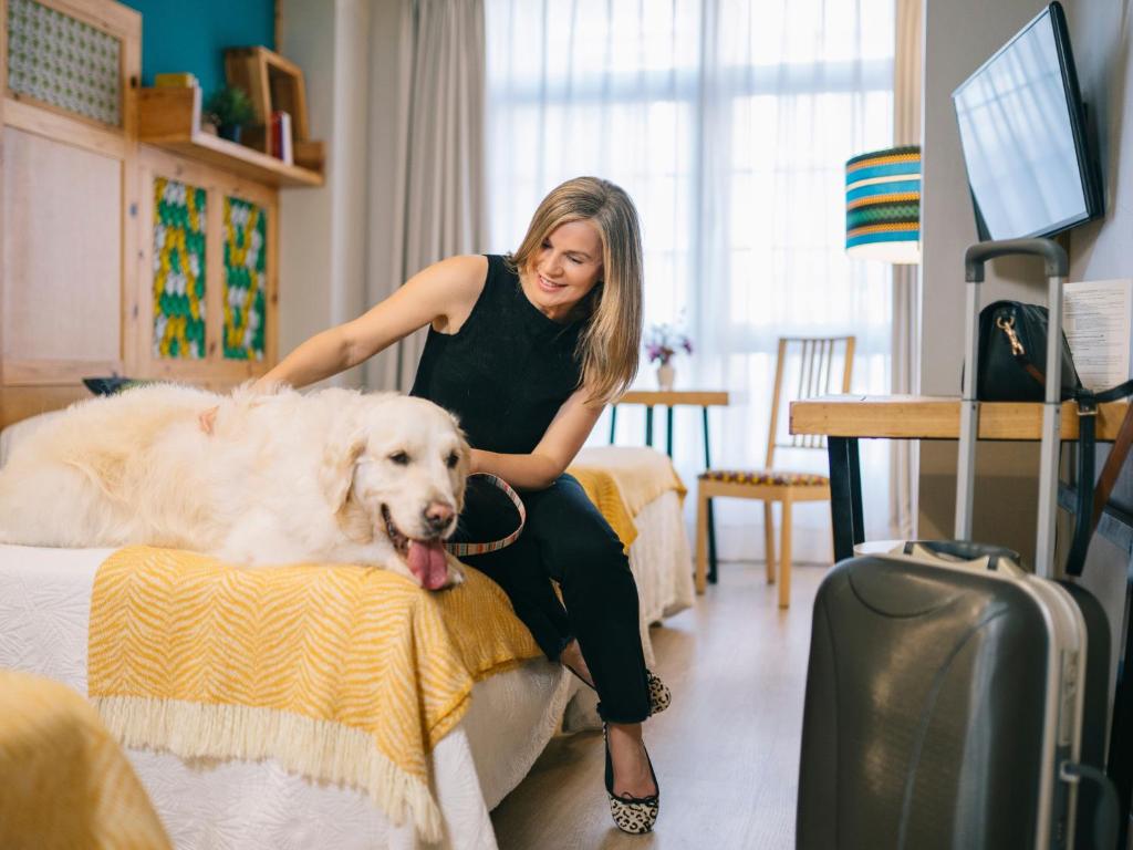 a woman sitting on a bed with a dog at Hotel San Miguel in Gijón