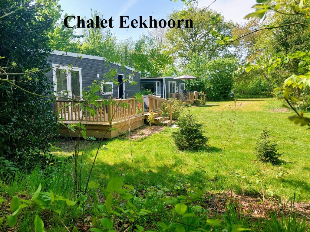 a garden view of a holiday cottage with a deck and a house at Erfgoed de Boemerang - Chalets in Meppen