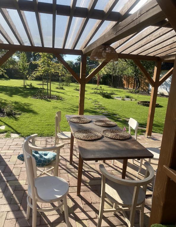 a wooden table and chairs under a wooden pergola at Szarvas és Bagoly Kalandház in Szarvas