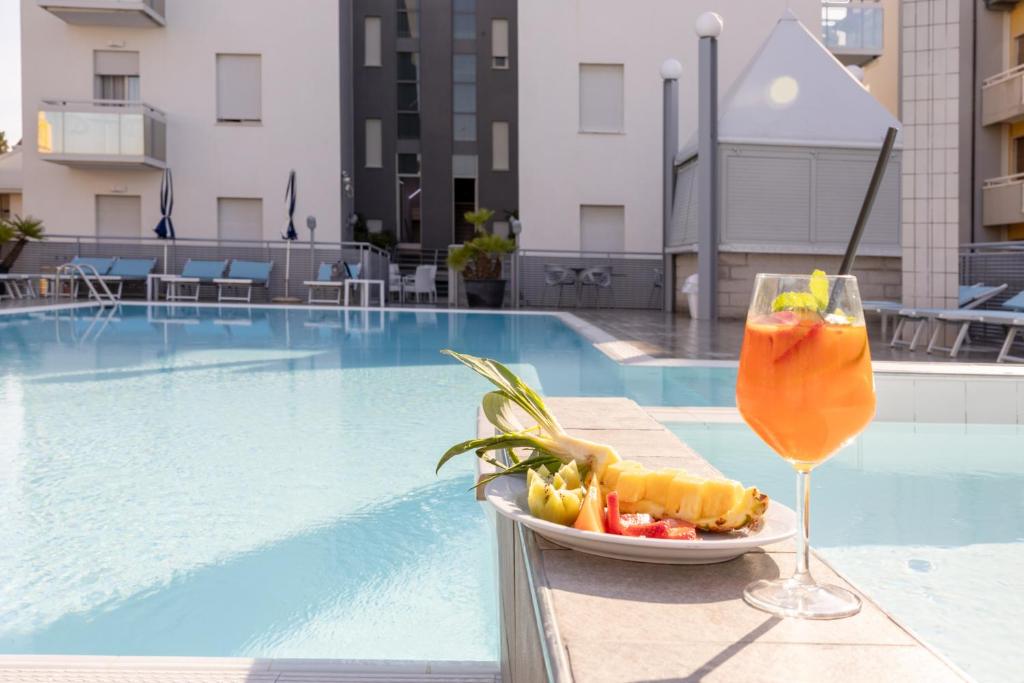 a plate of food and a drink on a table next to a pool at Hotel Bristol in Caorle