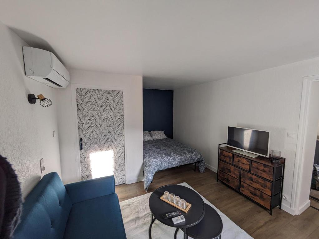 - un salon avec un canapé bleu et un lit dans l'établissement appartement climatisé Aubenas, à Aubenas