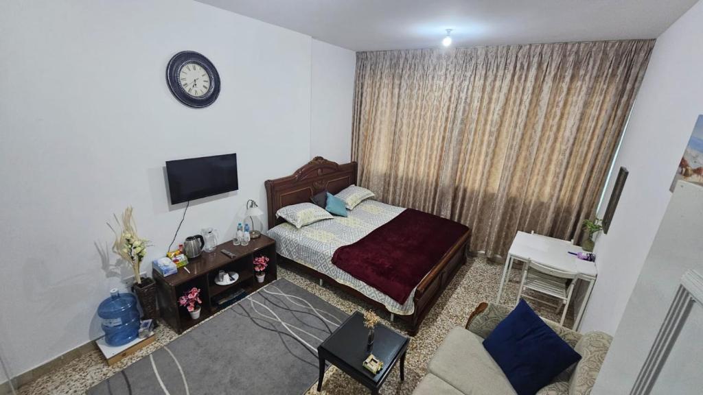 a bedroom with a bed and a tv and a couch at Furnished bedroom near Abu Dhabi Corniche in Abu Dhabi