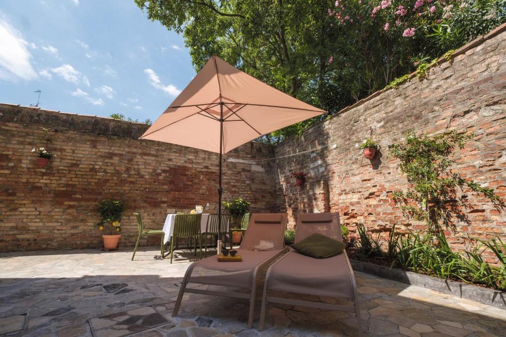 a patio with two chairs and an umbrella at Giselda Courtyard Retreat in Venice