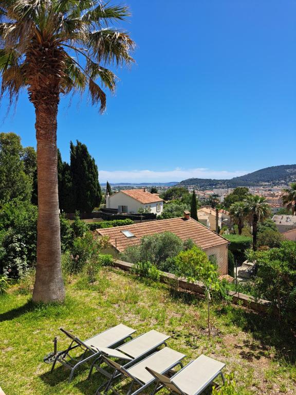 a group of picnic tables under a palm tree at Bas Villa, Vue mer, Centre ville, Paradis, calme in Hyères