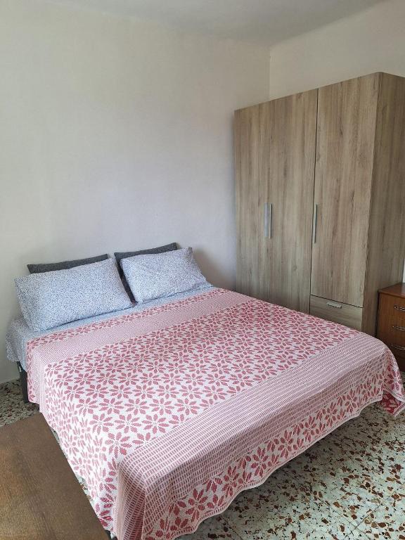a bedroom with a pink bed with blue pillows and a cabinet at Сozy House in Alicante