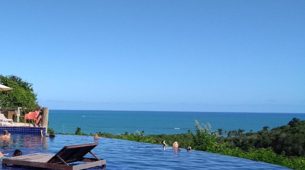 a swimming pool with people in the water at Bangalô no alto da colina no Villas do Pratagy - Maceió in Maceió
