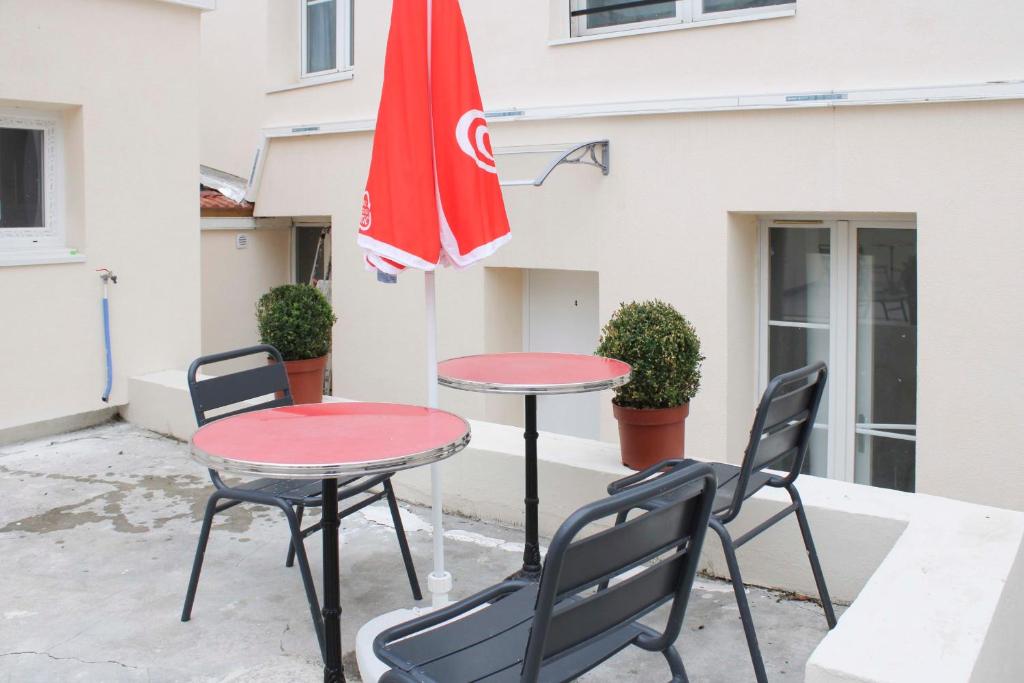 2 tables, des chaises et un parapluie rouge dans l'établissement Charming house with an outdoor terrace, à Ivry-sur-Seine