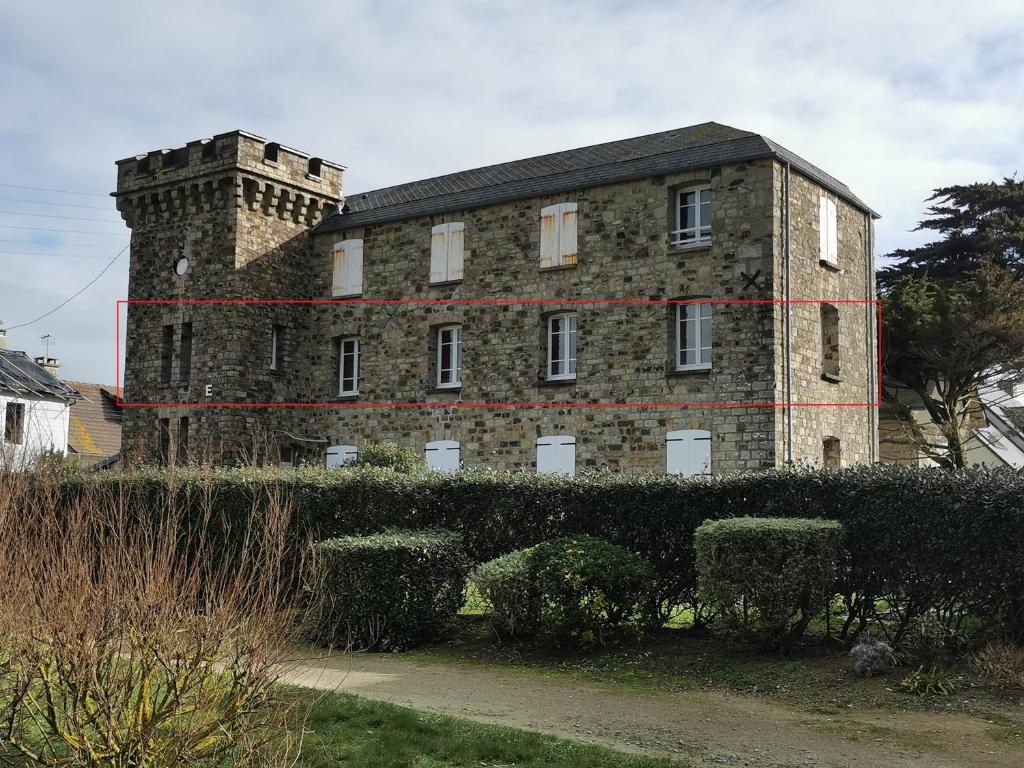 un grand bâtiment en briques avec une tour en haut dans l'établissement Appartement 50 M de la mer, à Barneville-Carteret