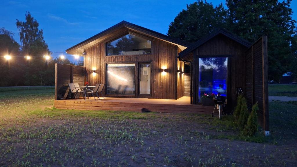 eine Holzhütte mit einem großen Fenster auf einem Feld in der Nacht in der Unterkunft Auksi puhkemaja-2 in Auksi