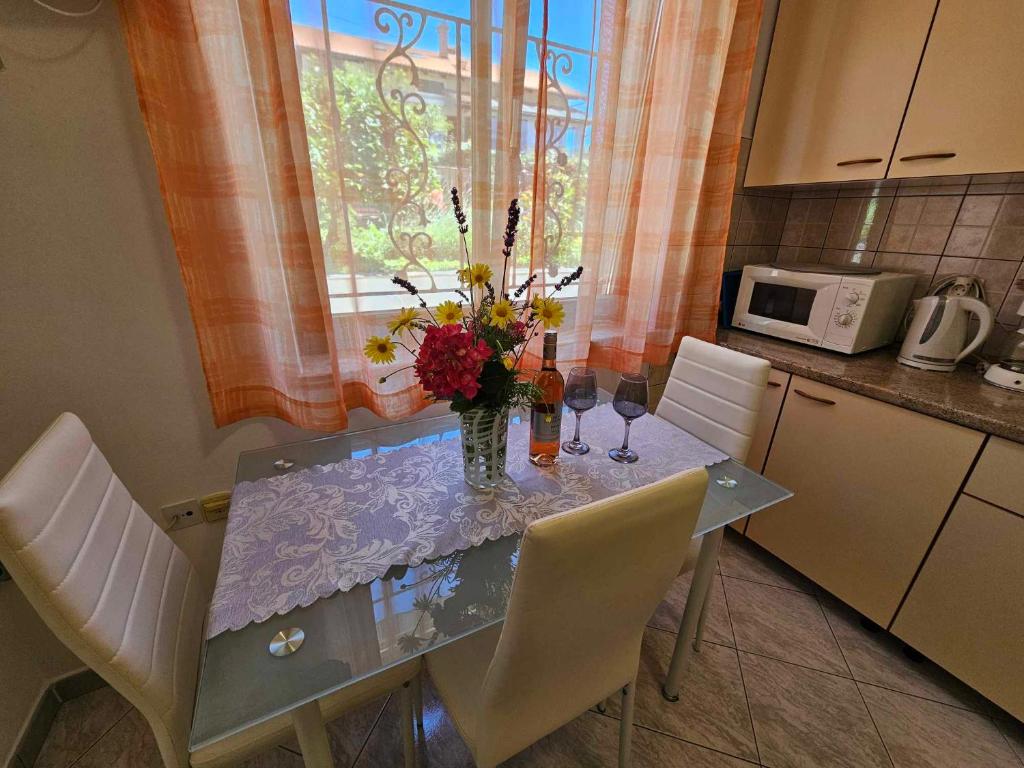 uma mesa de jantar com um vaso de flores em Apartmani Rita Oliva em Novigrad Istria