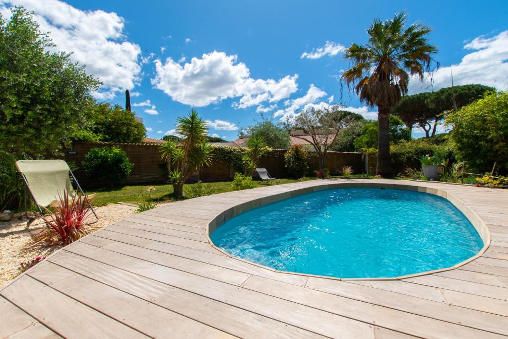 einen Pool im Garten mit Holzterrasse in der Unterkunft Très belle Villa classée 4* à La Grande Motte in La Grande-Motte