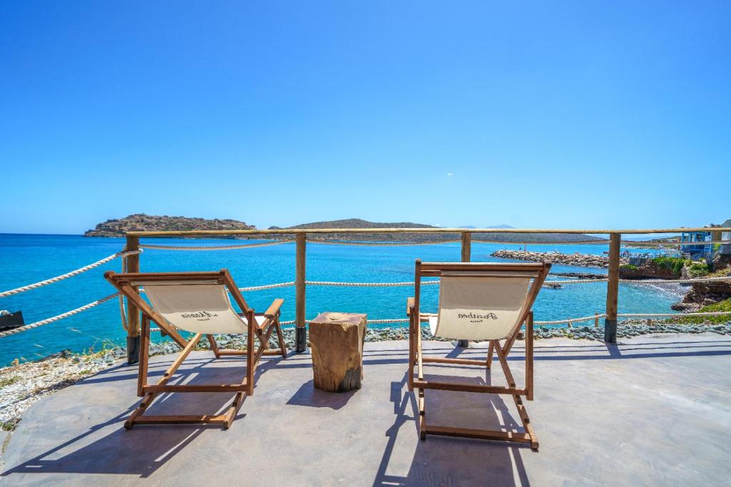 2 Stühle auf einer Terrasse mit Meerblick in der Unterkunft Petra Elounda Suites - Adults Only in Elounda