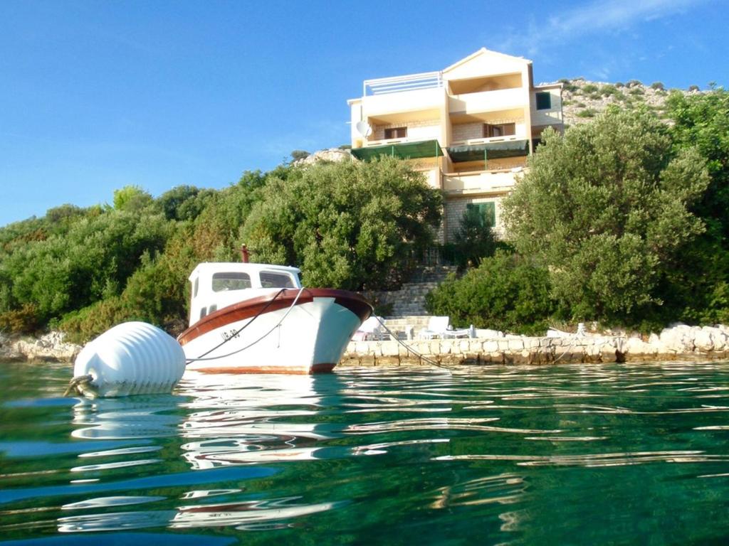 a boat in the water in front of a building at Apartments More in Skrivena Luka