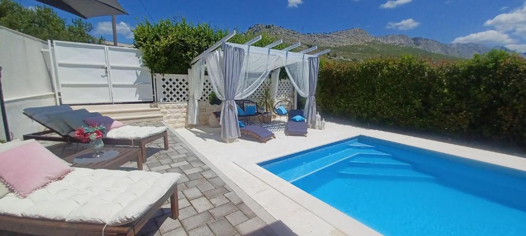 a swimming pool with chairs and a couch next to at House Matenda house in Solin