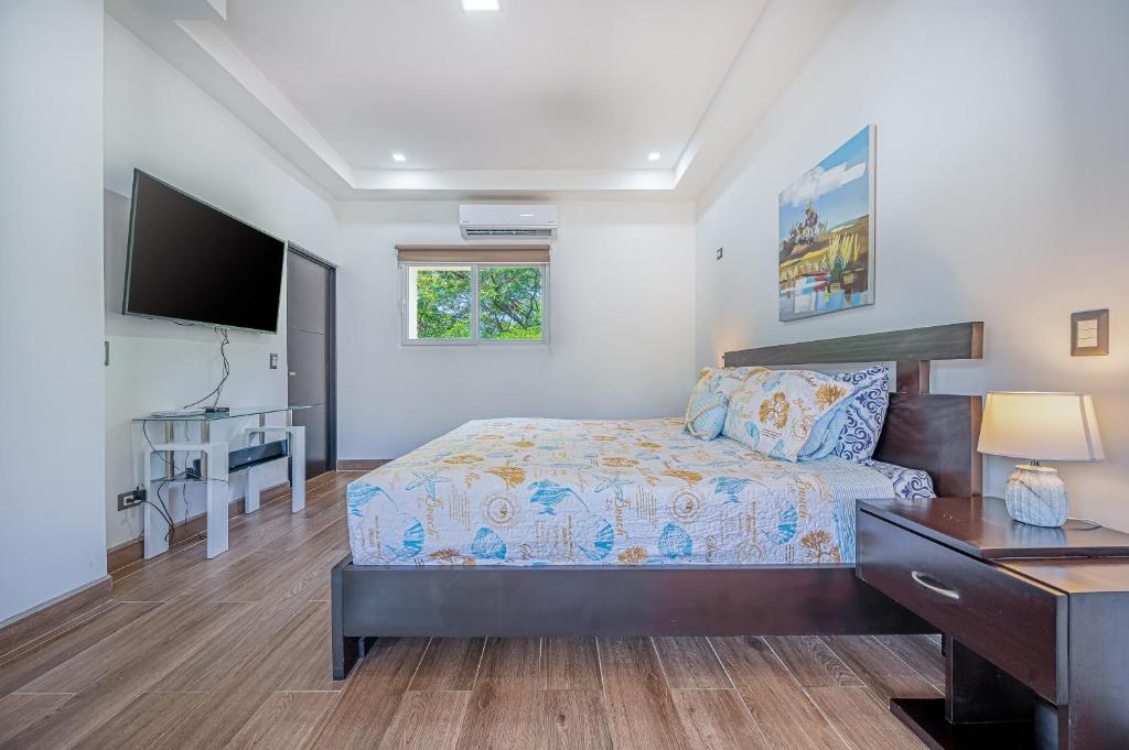 a bedroom with a bed and a desk and a television at Jacarandas 4 in Tamarindo