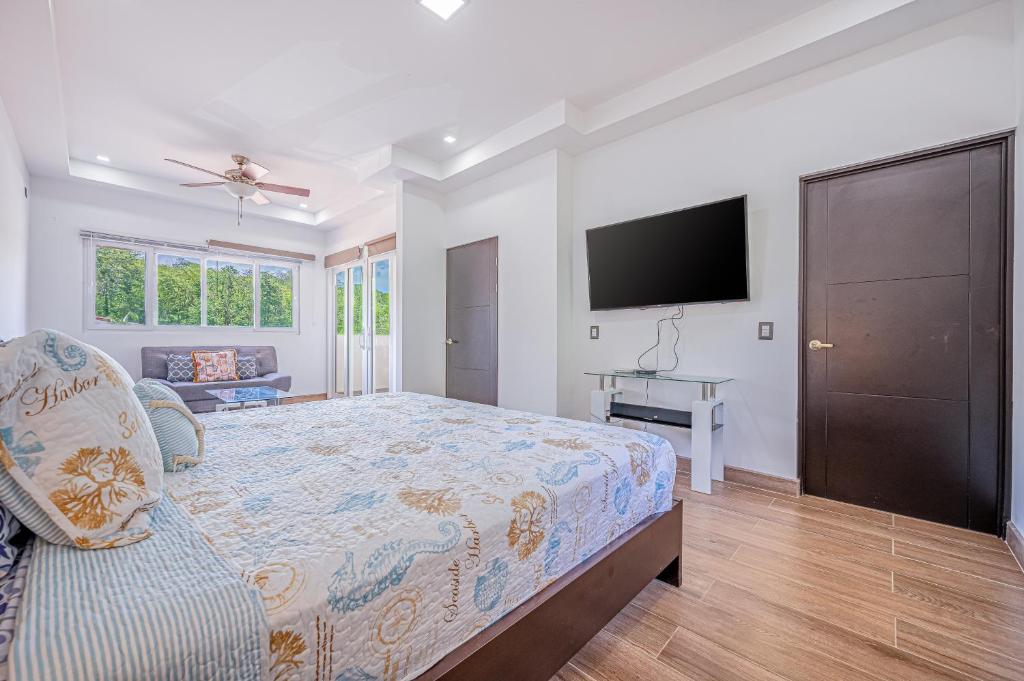 a bedroom with a bed and a flat screen tv at Jacarandas 4 in Tamarindo
