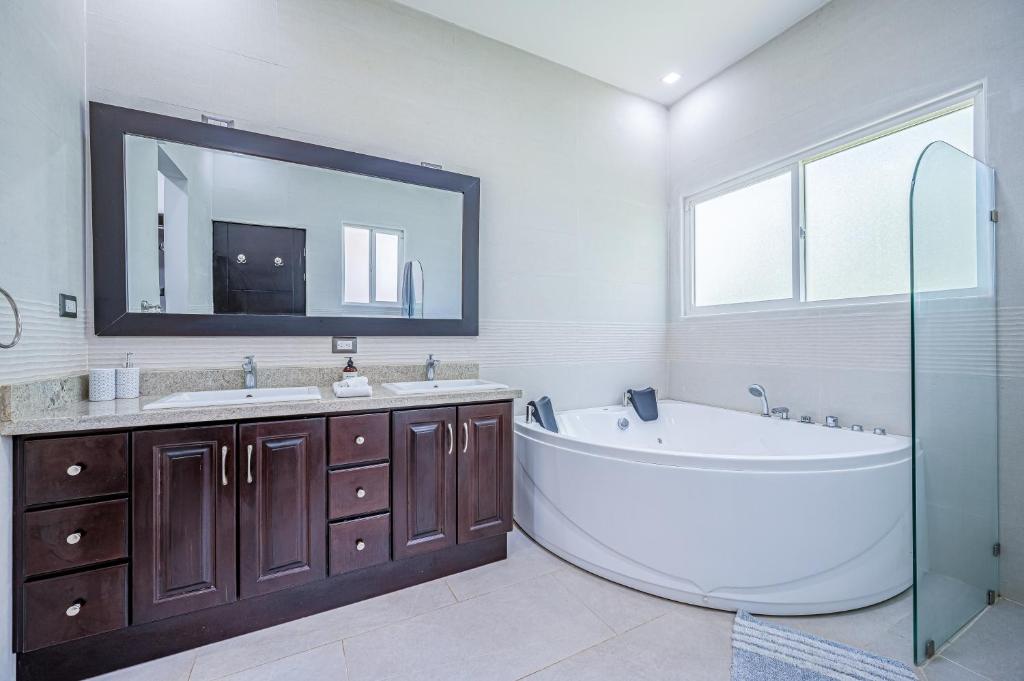 a bathroom with a tub and two sinks and a mirror at Jacarandas 4 in Tamarindo