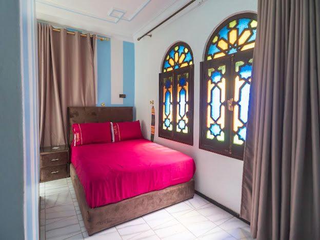 Schlafzimmer mit einem roten Bett und Buntglasfenstern in der Unterkunft Hotel Sevilla in Chefchaouen