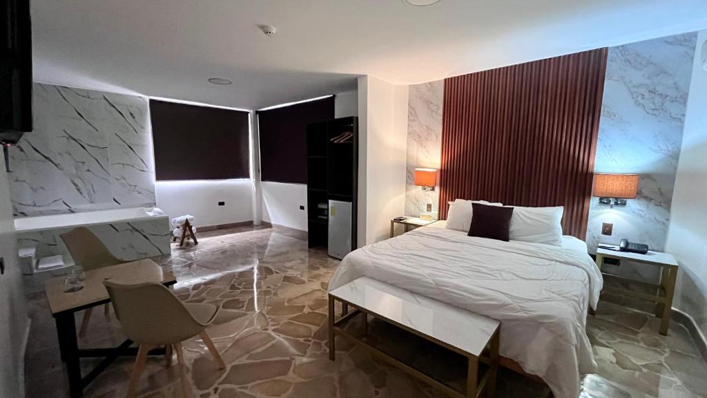 Hotel Varadero Internacional في غواياكيل: غرفة نوم بسرير ابيض ومكتب وكرسي