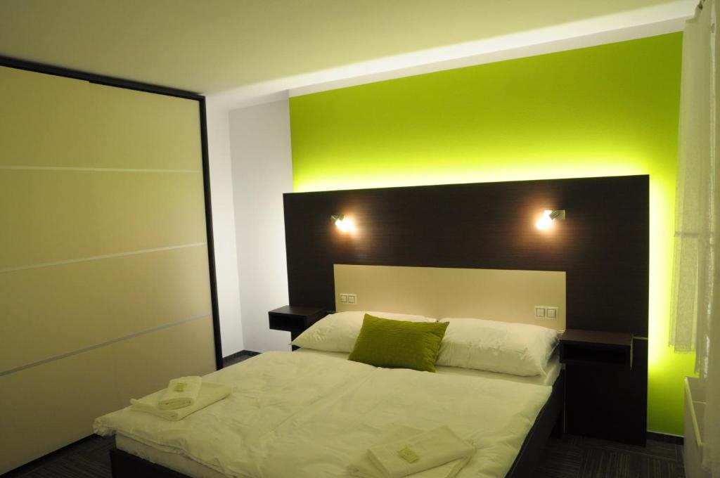 1 dormitorio con 1 cama con pared verde en Hotel Kaskada, en Ledeč nad Sázavou