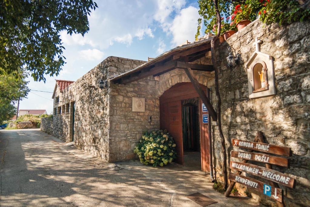 a stone building with a door and a street at Apartments & Rooms Konoba Tomić in Gornji Humac