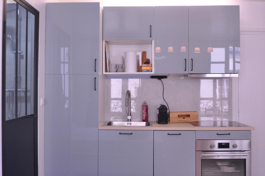 une cuisine avec des armoires blanches et un évier dans l'établissement Appt Paris11 Charonne, à Paris