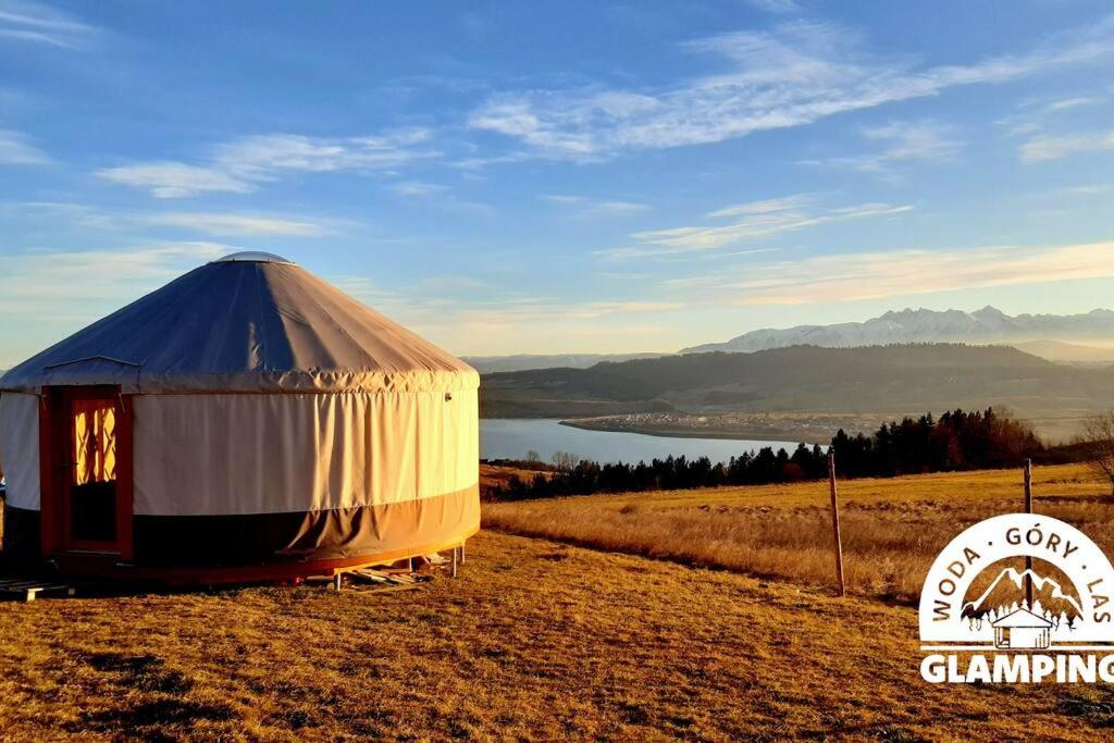 a yurt on a field with a view of a lake at Woda Góry Las - glamping CAŁOROCZNY in Szlembark