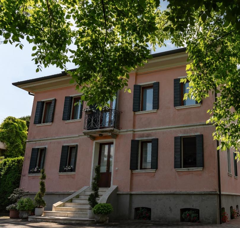 ein großes rosafarbenes Gebäude mit schwarzen Rollläden in der Unterkunft Villa Trevisi - APARTMENT in Treviso