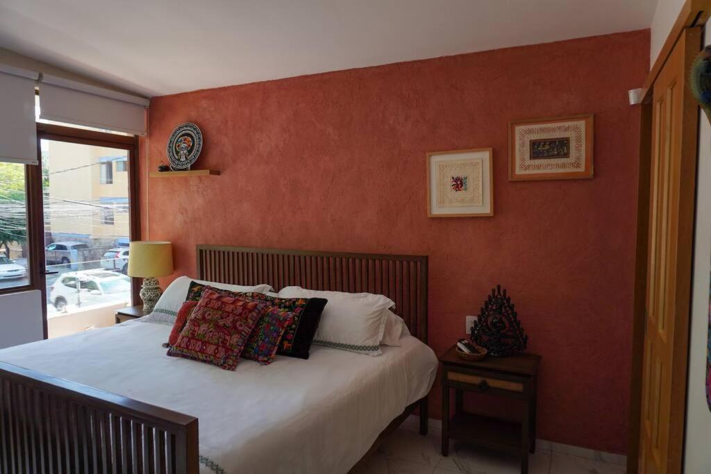 a bedroom with a bed with a red wall at Casa Nawuales - Terraza - Guadalajara céntrico in Guadalajara