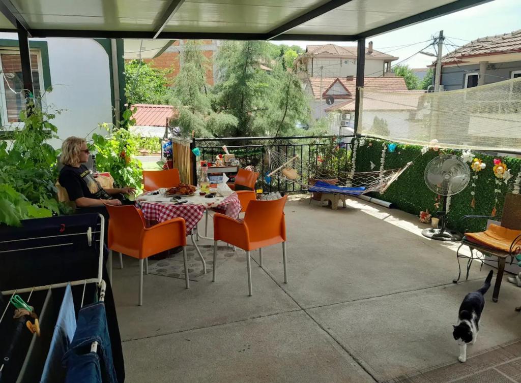 Eine Frau, die an einem Tisch auf einer Terrasse mit einer Katze sitzt. in der Unterkunft Stay with Adem in Skopje