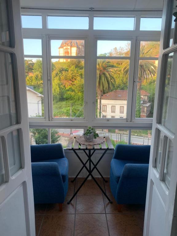 a room with two chairs and a table and windows at La casita de Kalani in Comillas