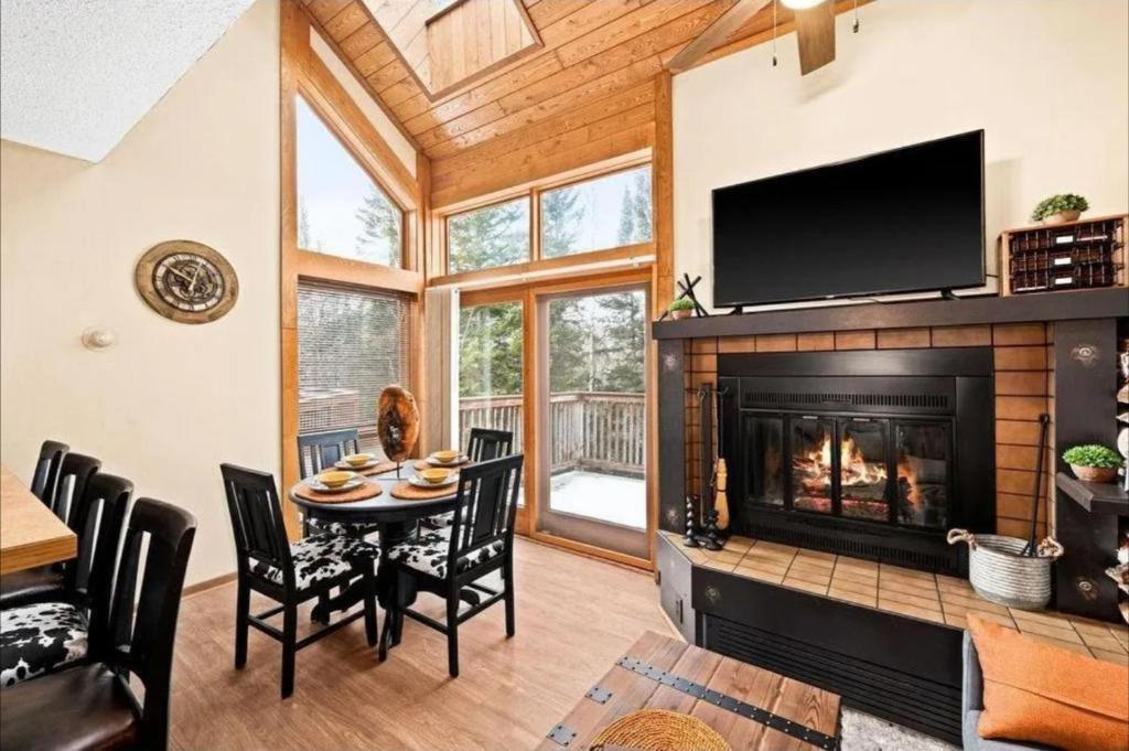 Una sala de estar con chimenea y una mesa y sillas. en Charming Lutsen Ski-In Ski-Out Townhome with Pools and Hot Tub, en Lutsen