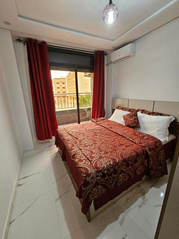 a bedroom with a bed with red curtains and a window at Appartement moderne près de la corniche in Nador
