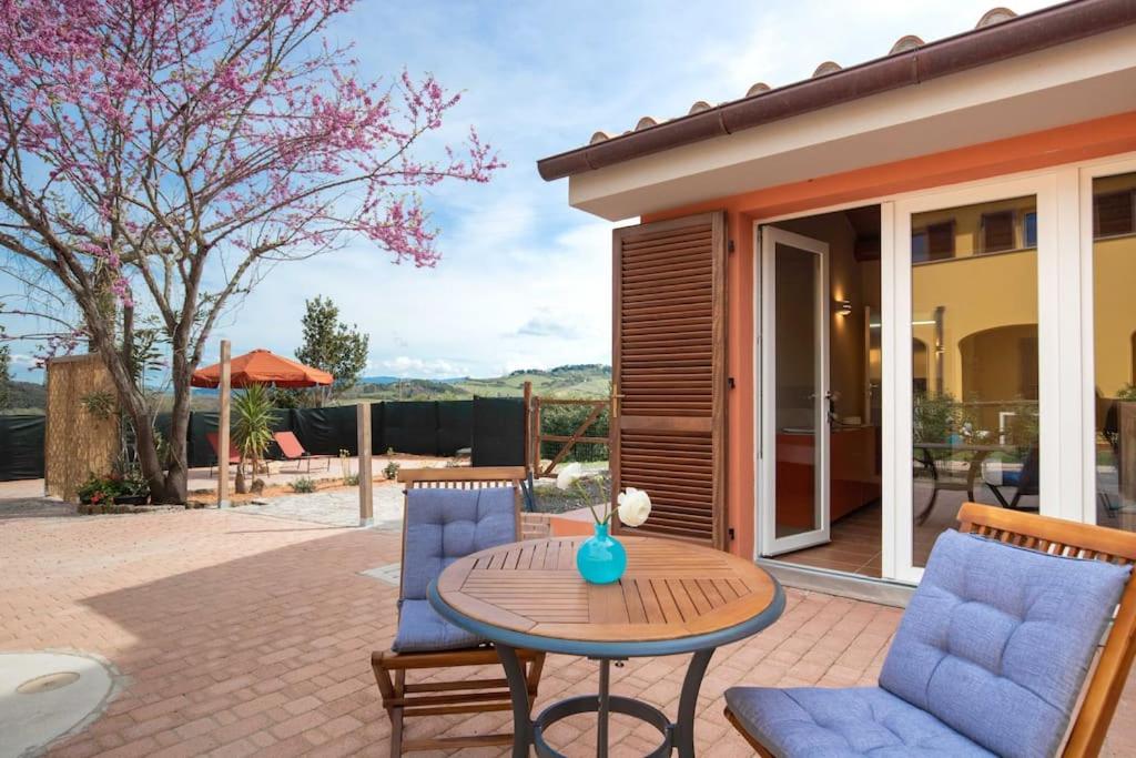 a patio with two blue chairs and a table at Casa Melatina ToscanaOneHH in Riparbella
