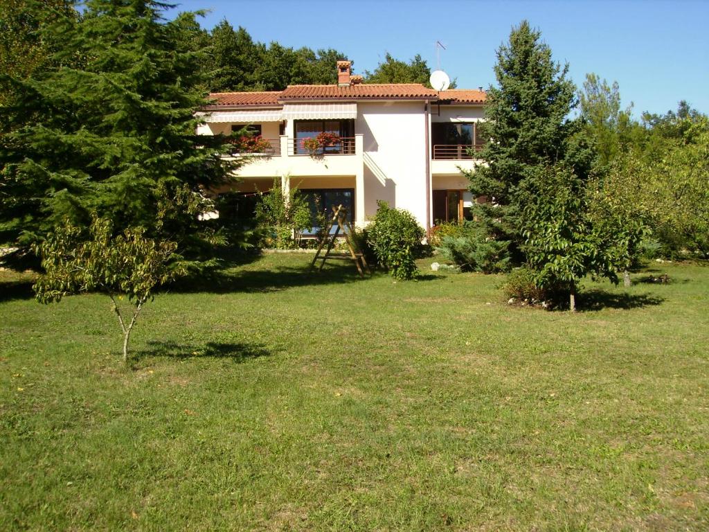 ein Haus in einem Hof mit Bäumen und Gras in der Unterkunft Apartment Neda Z-velika okućnica, besplatni parking i optički wi-fi in Labin