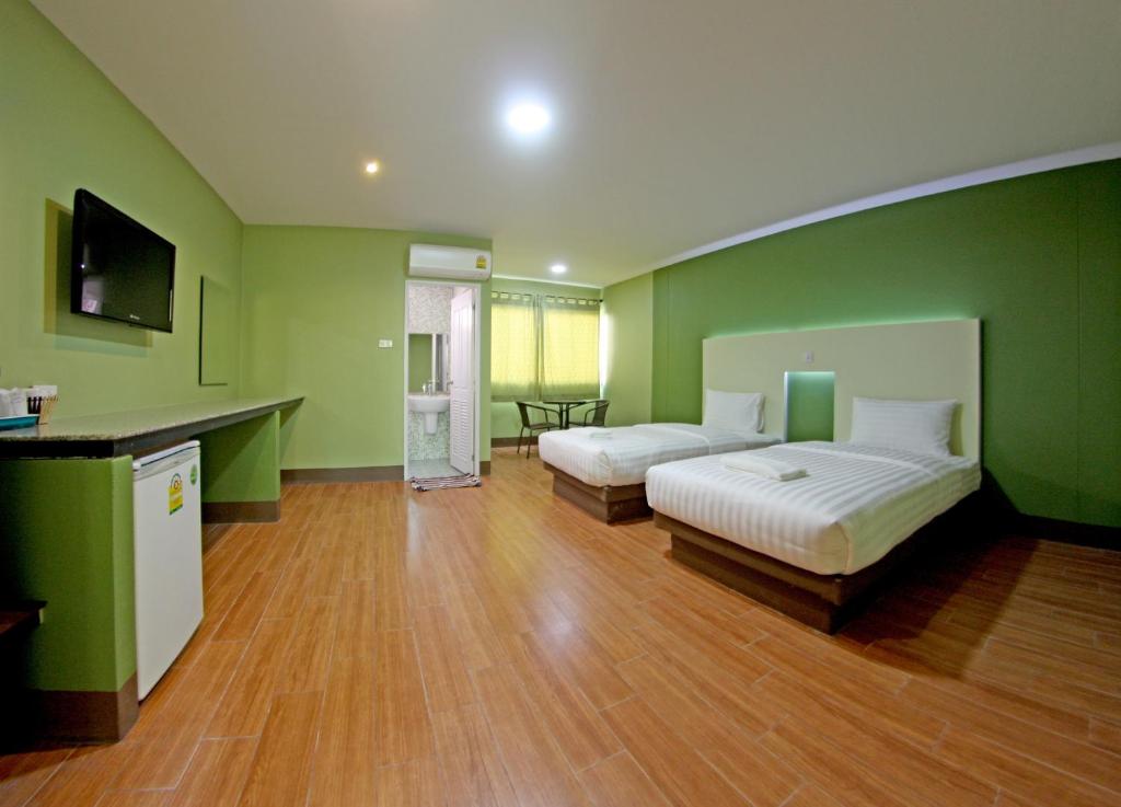 a green room with two beds and a table at Central Park Hotel in Sing Buri