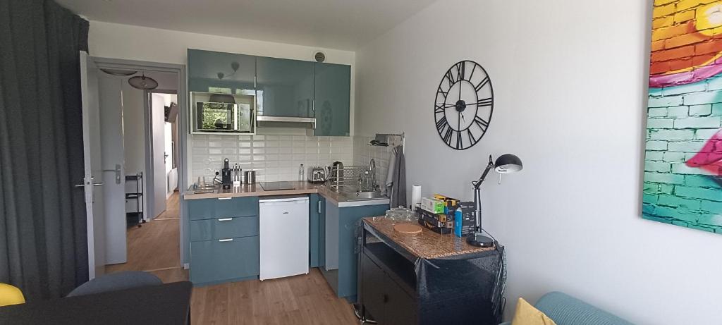 une cuisine avec des placards bleus et une horloge murale dans l'établissement Actarus-SILS - T1 28 M2, à Caen