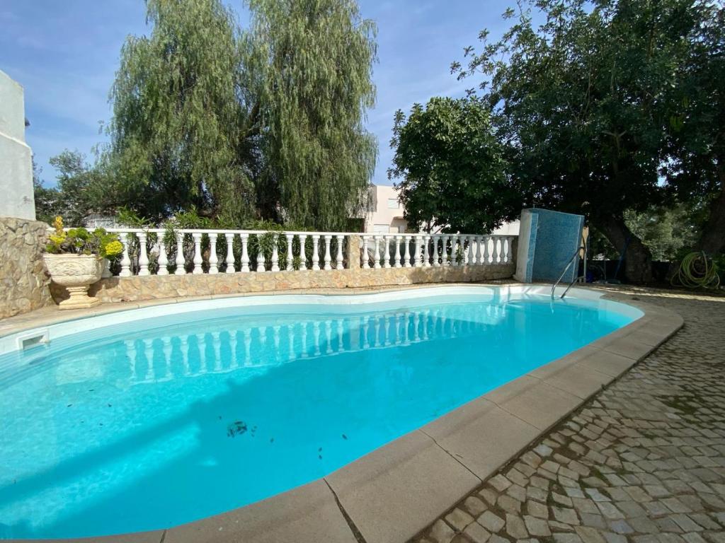 een blauw zwembad met een wit hek bij Alcaria Pool House in Altura