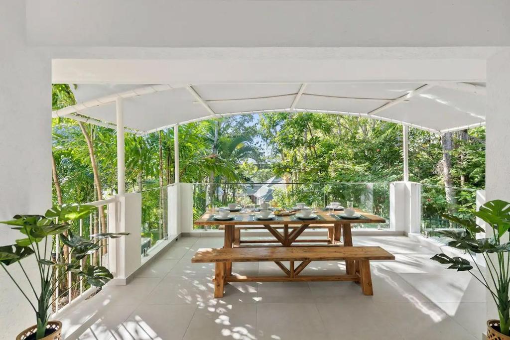 a dining room with a wooden table on a porch at Belle Escapes Sandpipers Beach House in Palm Cove