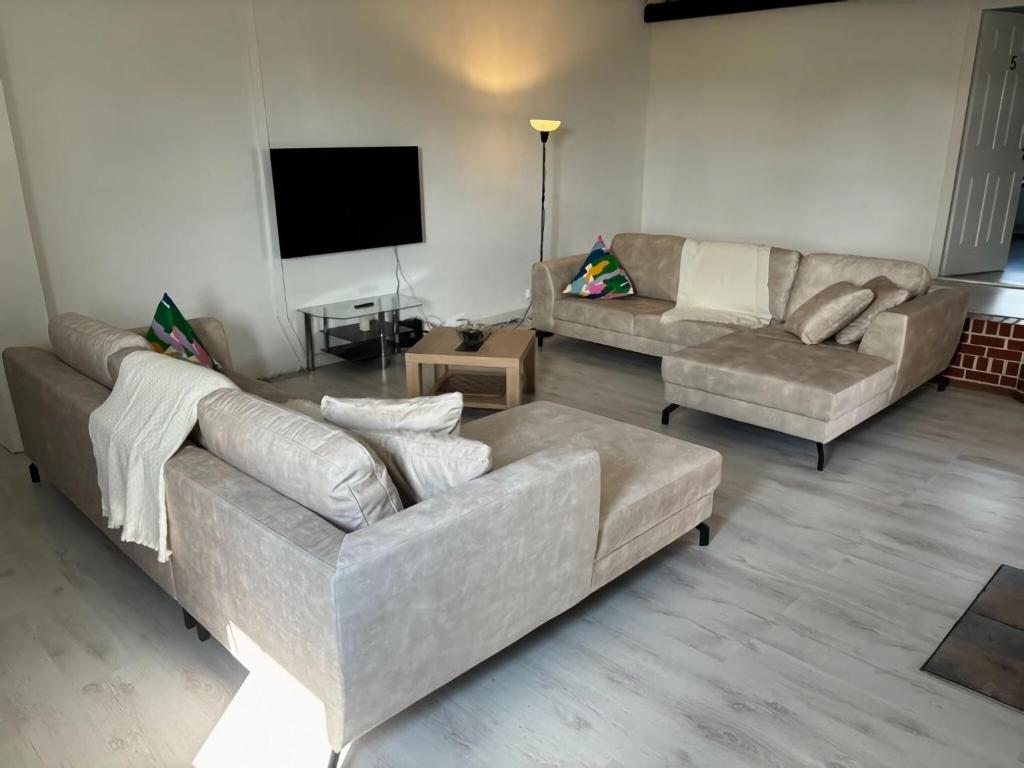 een woonkamer met 2 banken en een flatscreen-tv bij Spacious holiday home with garden in Elsenborn