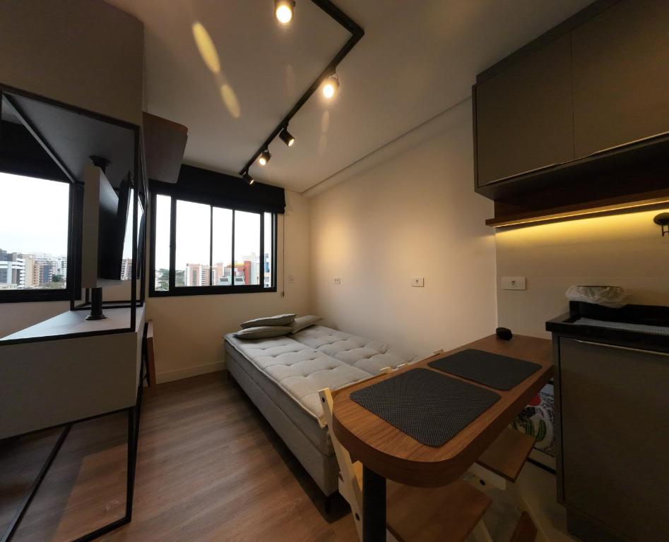 Una habitación con una cama y una mesa dentro. en Studio Walk B - 807, en Curitiba