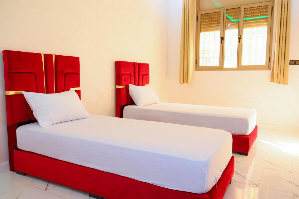 2 Betten mit roten Kopfteilen in einem Zimmer in der Unterkunft Bel appartement-Haut débit WIFI in El Aaiún